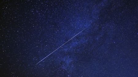 A meteor is pictured shooting diagonally through a starry night sky.