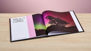 The Mixbook photo book sits open, turned to pages featuring an Aurora Borealis photo with a large caption and a pink rectangle spanning the height of the image.