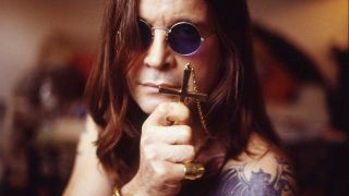 Ozzy Osbourne in sunglasses holding a cross