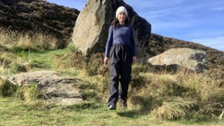 Hiker walking towards camera with large boulder behind