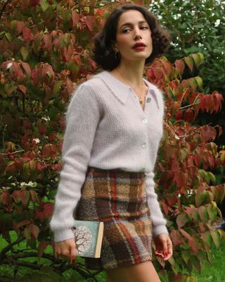 Melodiebance wears a plaid skirt with a collared cardigan sweater.