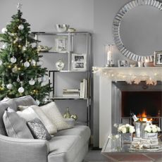  Silver chrome festive living room, Christmas tree in small space behind sofa, lit fire.