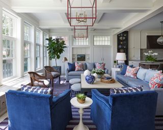 open living room with blue sofas, blue striped rug, red accent cushions