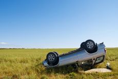 Car crashed on country road with field and sky