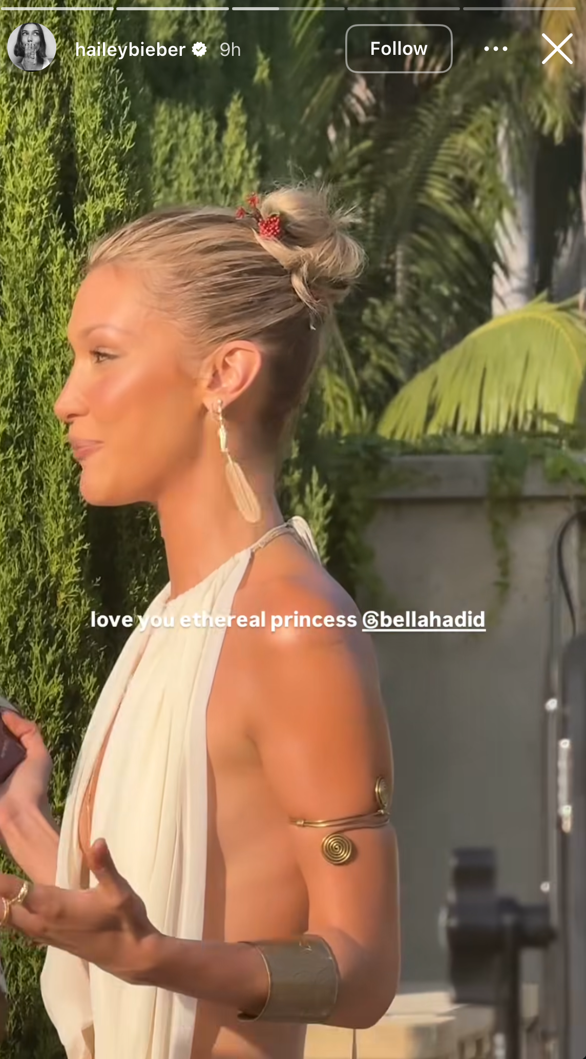 bella hadid wearing a backless white dress with gold accessories and a raspberry hair pin