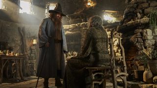 Tom Bombadil stands over The Stranger sitting in a chair in The Rings of Power season 2