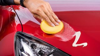 Wax being applied to the bonnet of a red car