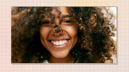Portrait of smiling young woman with brown curly hair, looking at camera