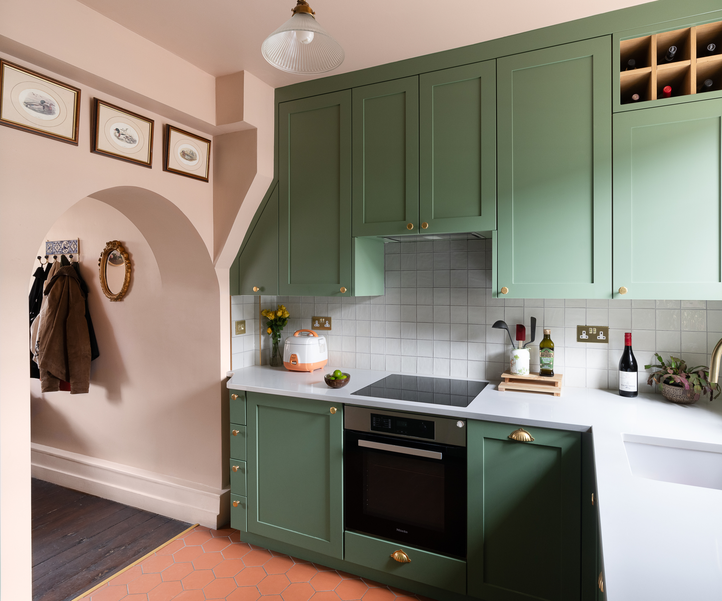 kitchen extension with green cabinets and pink painted wall with archway leading to rest of house