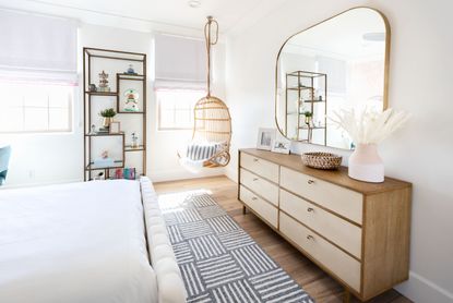 A bedroom with a long, rectangular mirror opposite the bed