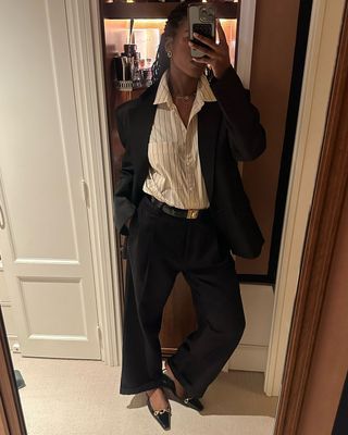 fashion influencer @nlmarilyn wearing a striped button-down shirts, black jeans, a Saint Laurent belt and slingback flats