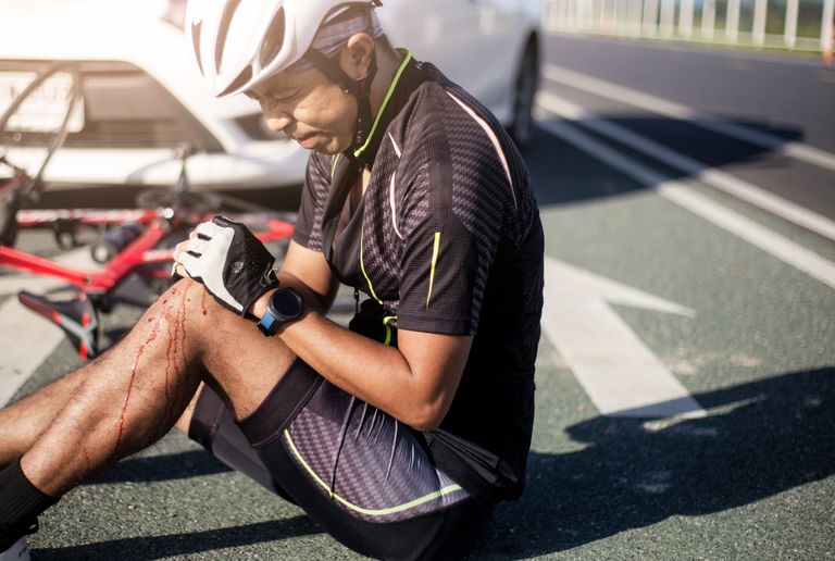 Cyclist with knee injury awaits first aid