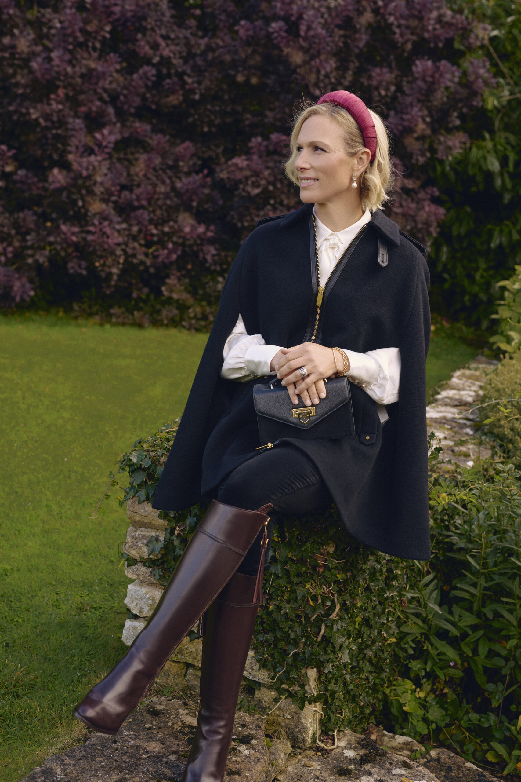 Zara Tindall official brand ambassador wearing Fairfax &amp;amp; Favor Ada Cape, Mini Loxley bag and Regina boots