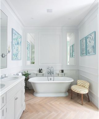 bathroom with white walls and freestanding bathtub and patterned accent chair and wooden floors