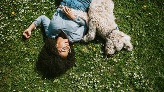 Woman laying in the grass with her dog