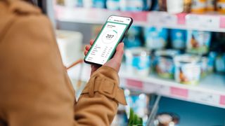 Woman looking at how many calories there are in ice cream on app while shopping in the supermarket