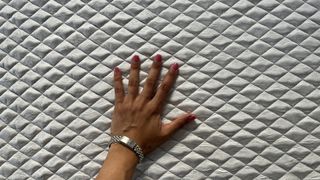Reviewer's hand resting on cover of Leesa Sapira mattress