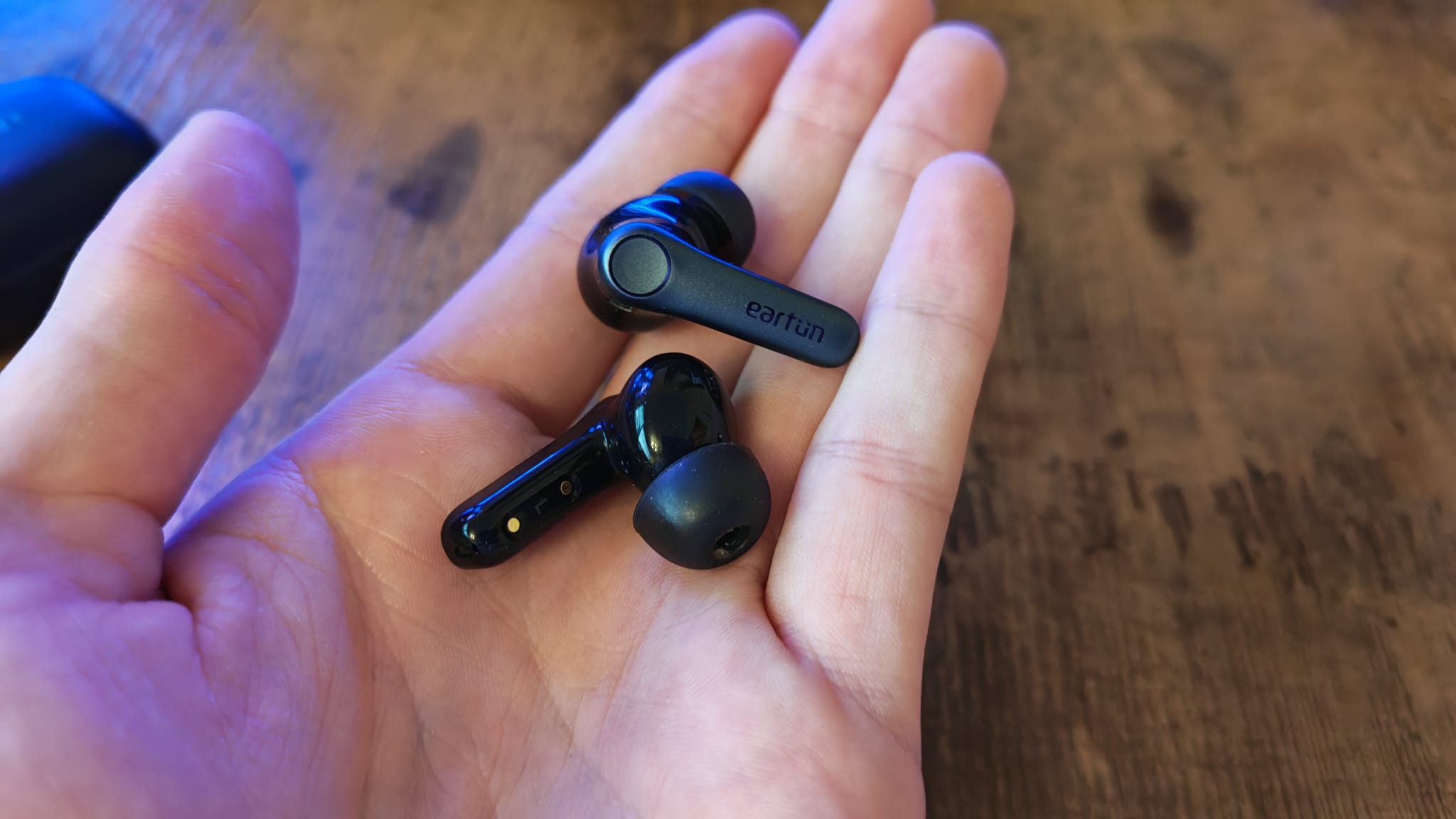 A reviewer holding both EarFun Air Pro 4 earbuds