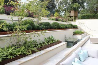 sunken patio area surrounded by stepped terrace with seating and raised beds