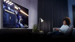 Une femme regarde un grand téléviseur dans un salon gris.