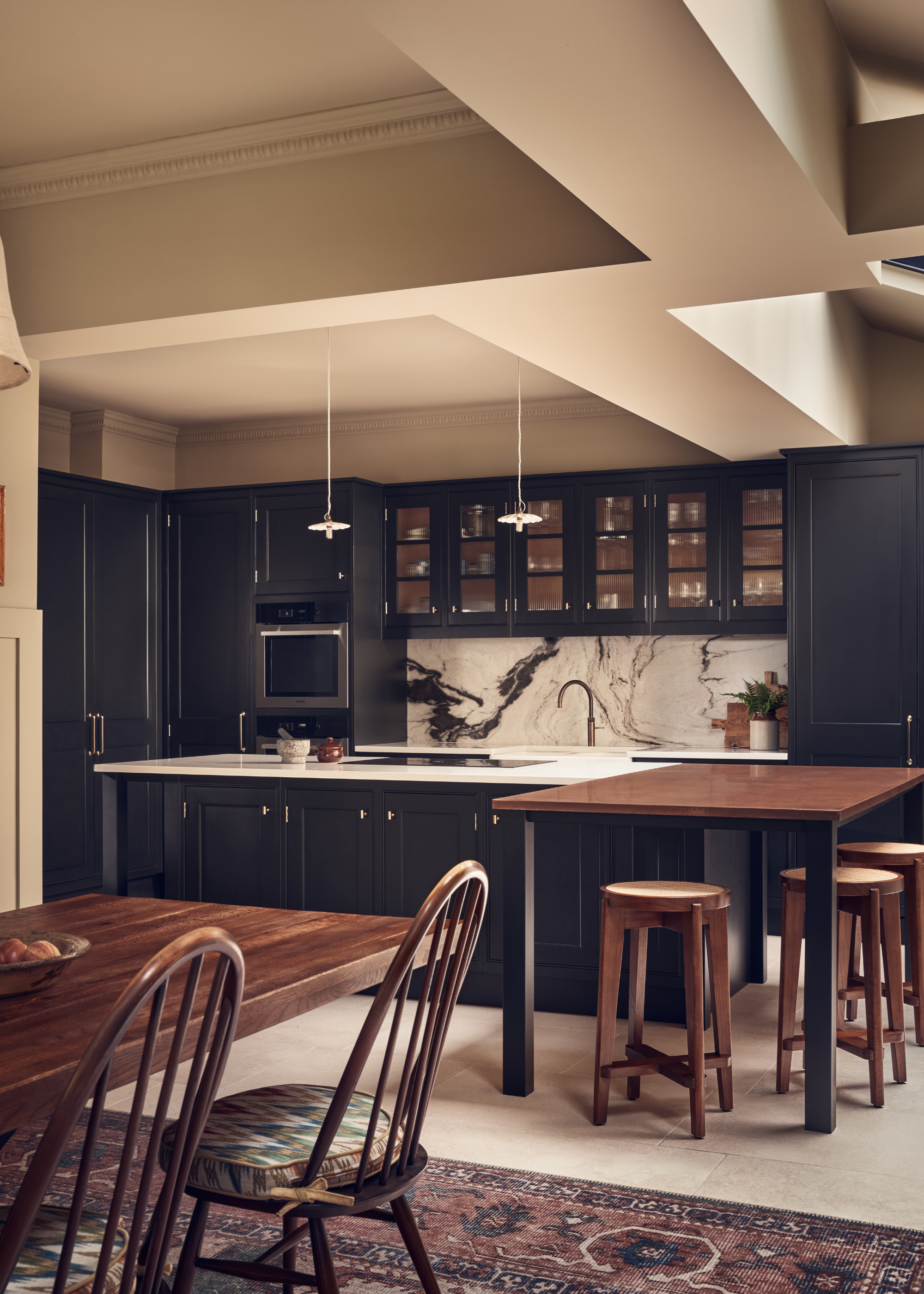modern, open plan kitchen with dark cabinets, a marble backsplash, and a split island, leading into a dining area