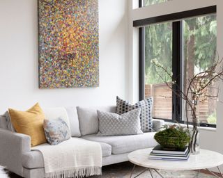 modern living room with white walls, neutral sofa and colorful artwork