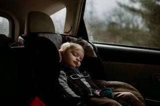 A young boy asleep in a car seat