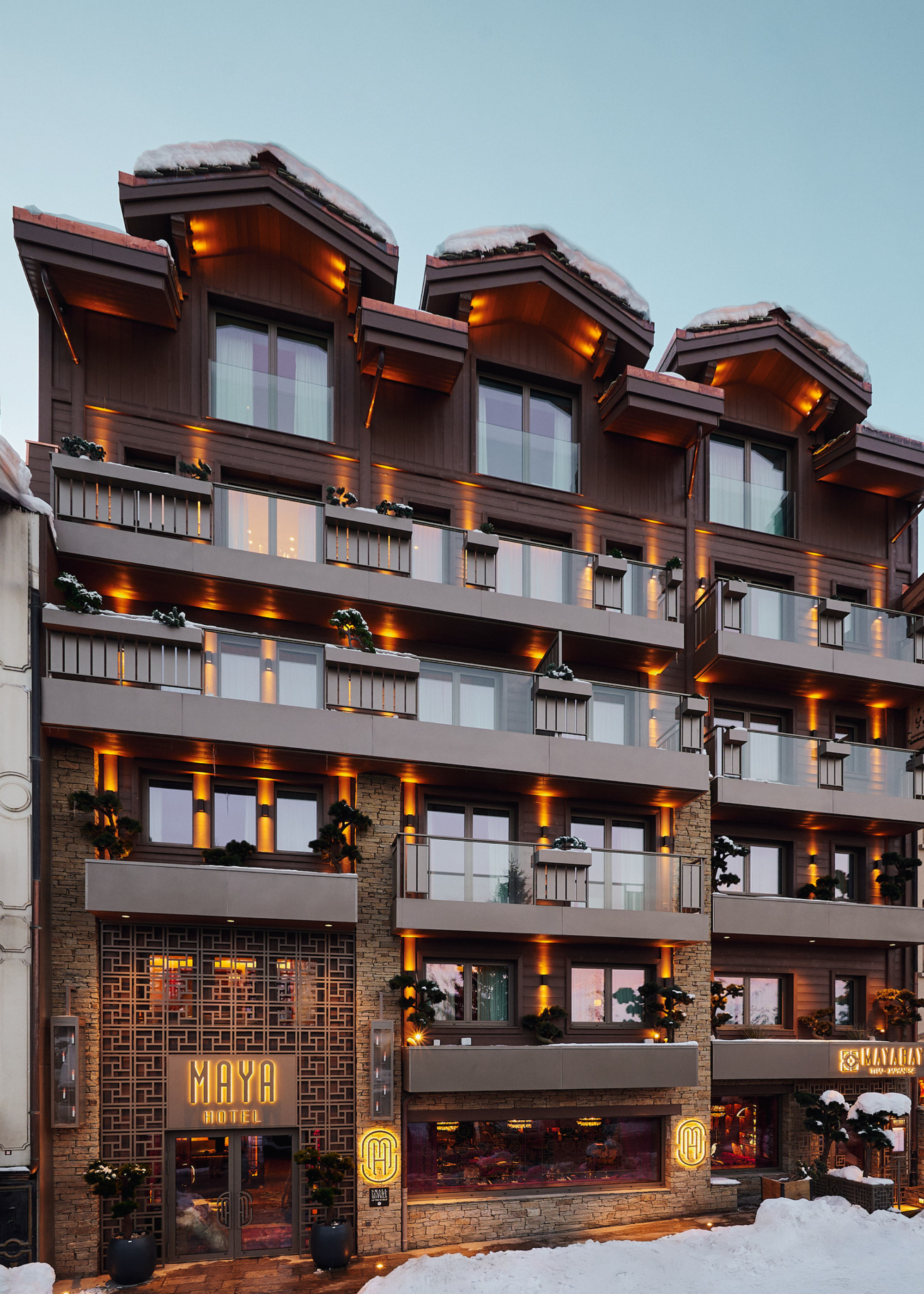 Maya Hotel Courchevel 1850 facade at dusk with the exterior lights on highlighting the luxurious chalet style design