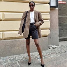 @sylviemus_ wearing black denim shorts and a blazer 