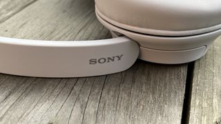 The Sony WH-CH720N headphones in white on a wooden background
