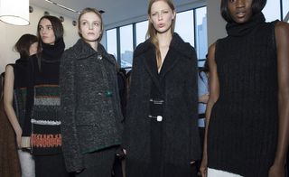 Female models in black clothing line up for runway