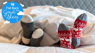 Two feet in cozy winter socks sticking out from under the duvet on a bed
