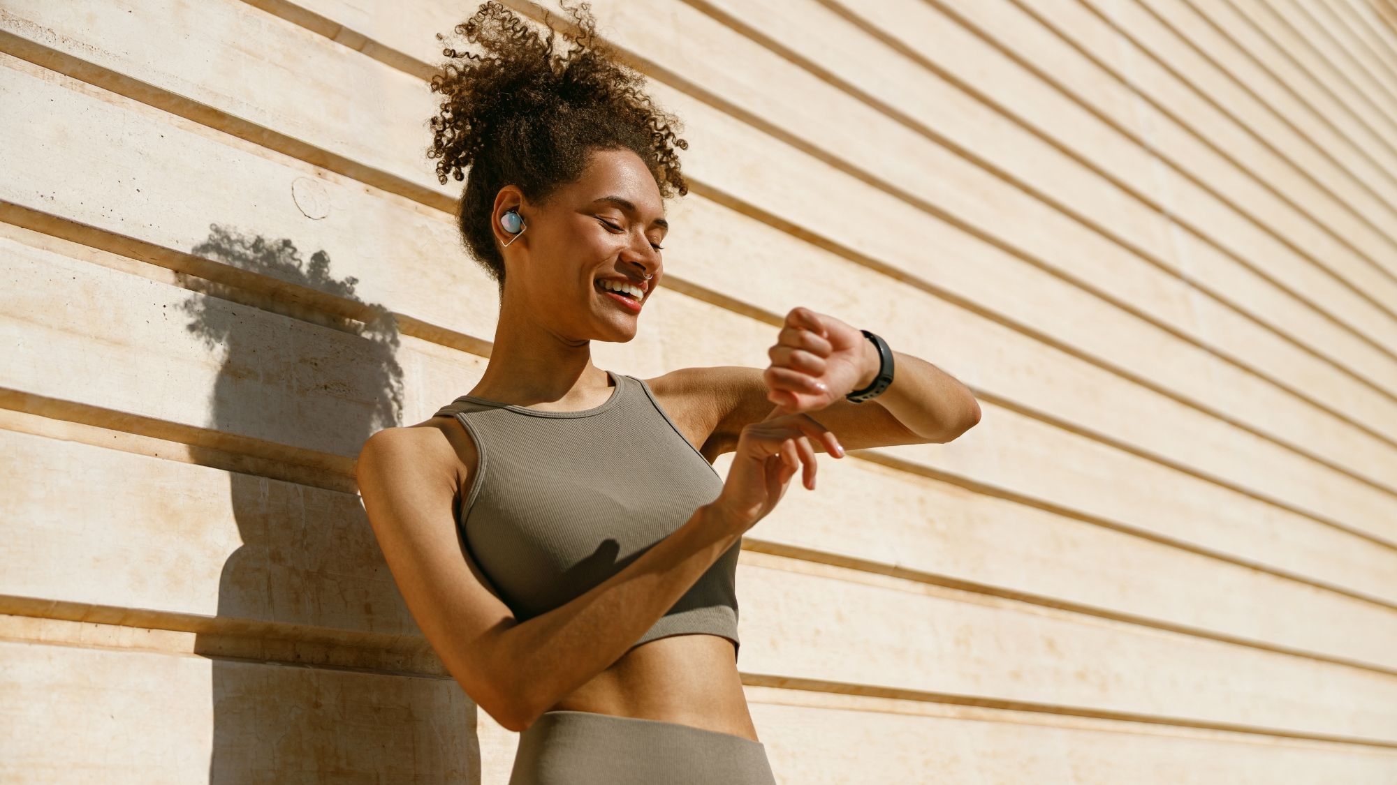A woman mid run, pausing for a break and looking at her fitness watch