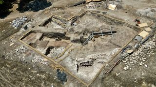Photograph of an aerial view of an archaeological site and an excavated steel structure.