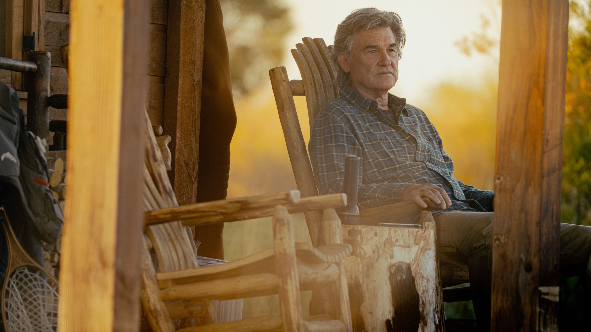 a production image from The Madison showing Kurt Russell sitting on a porch of the cabin