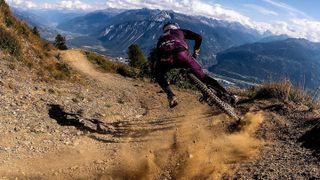 A rider drifting through a dusty corner with a mountainous backdrop