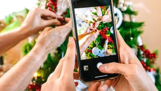 taking a photo of people decorating a christmas tree