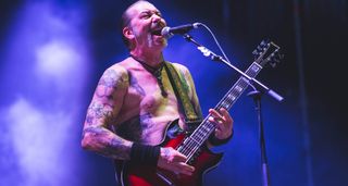 A shirtless Matt Pike plays his custom Woodrite doublecut onstage