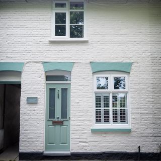 house exterior with white brick wall and teal door