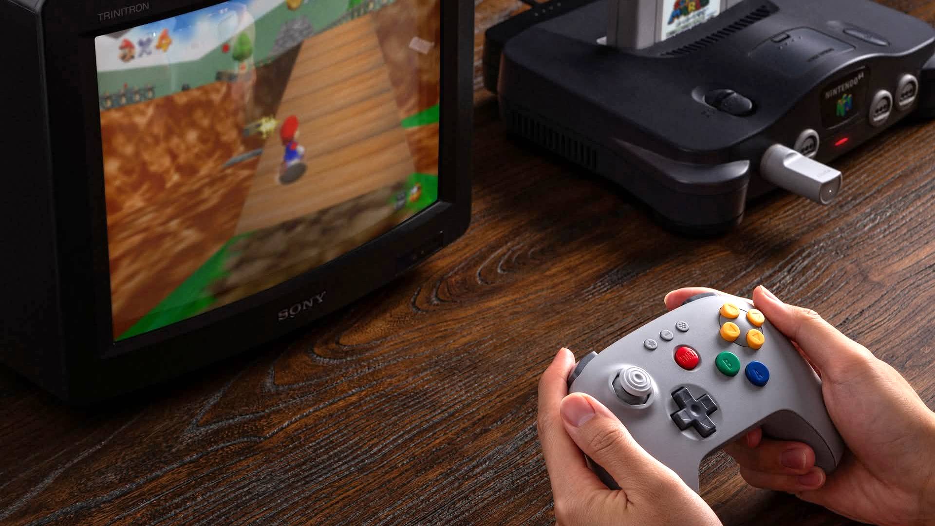 Hands using 8Bitdo N64 controller 2.4G with Nintendo N64 connected to Sony CRT TV with Super Mario 64 on screen.
