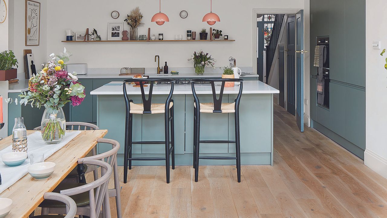 Green open plan kitchen with island, dining table and berber rug