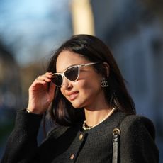 woman in black jacket, white sunglasses and pearl necklace