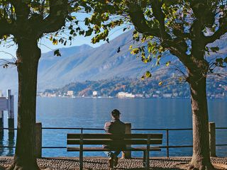 A man on a bench watches scenic mountain view.