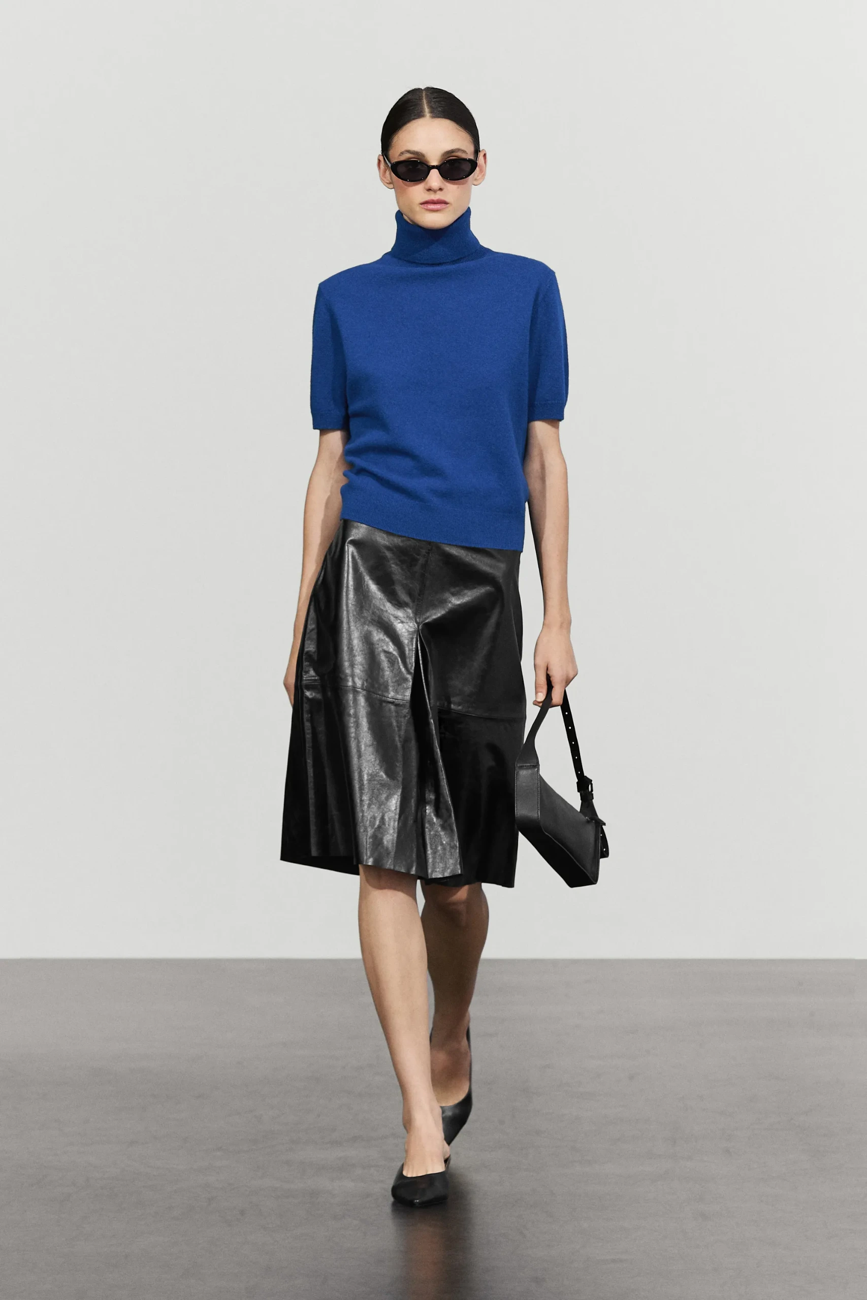 A model wears a blue Massimo Dutti short sleeve jumper, patent leather skirt and ballet flats