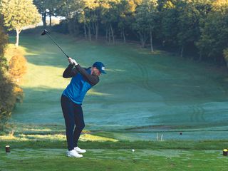 Adam Harnett hitting a tee shot with driver on a cold, wet day