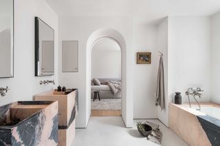 a minimalist bathroom with a pink marble bath