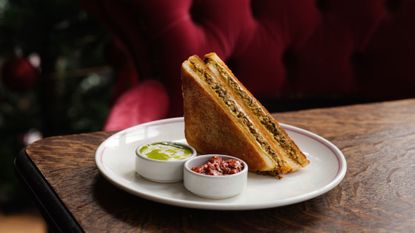 turkey keema and cheese toastie on a white plate with accompanying sauces