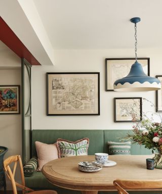 dining room with wooden table and green upholstered bench and blue pendant light