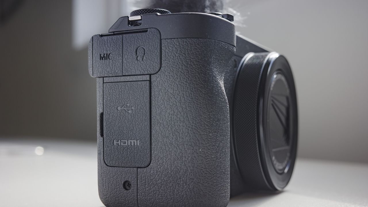 Closeup of Canon PowerShot V1 compact vlogging camera's mic and headphone ports, on a white desk