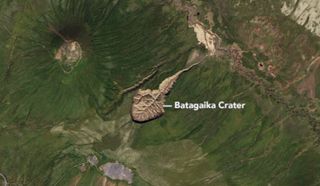 aerial view of a huge crater shaped like a tadpole on a green landscape